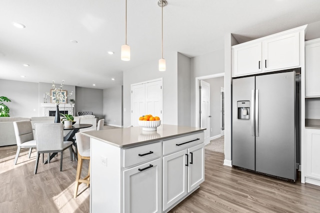 kitchen featuring light wood-style flooring, a fireplace, white cabinetry, and stainless steel refrigerator with ice dispenser