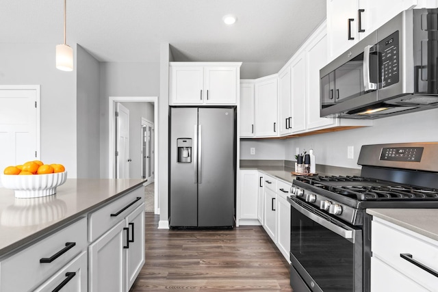 kitchen with recessed lighting, dark wood-type flooring, appliances with stainless steel finishes, white cabinetry, and decorative light fixtures