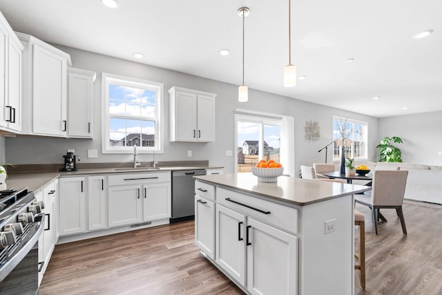 kitchen featuring a sink, a kitchen island, light wood-style floors, and appliances with stainless steel finishes