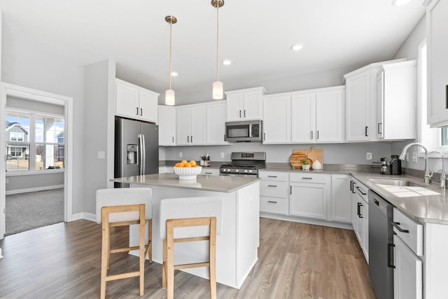 kitchen featuring light countertops, a kitchen breakfast bar, white cabinets, stainless steel appliances, and a sink