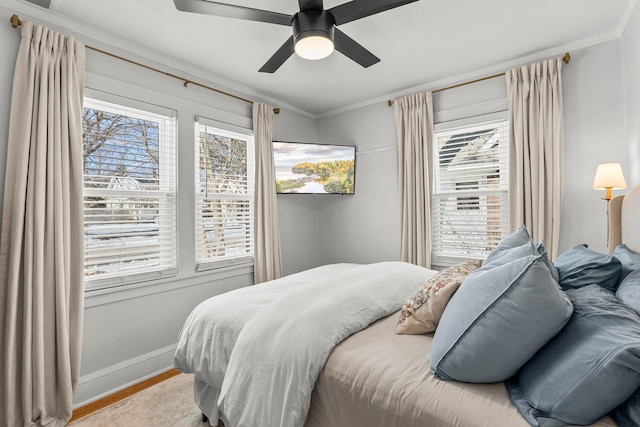 bedroom featuring crown molding, wood finished floors, baseboards, and ceiling fan