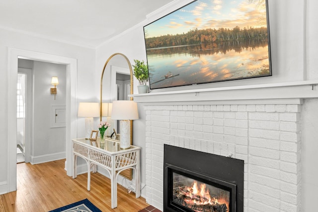 room details featuring a brick fireplace, crown molding, baseboards, and wood finished floors