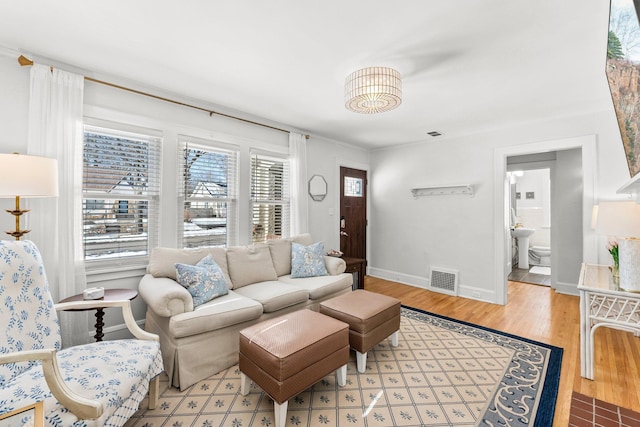 living area featuring visible vents, baseboards, and wood finished floors