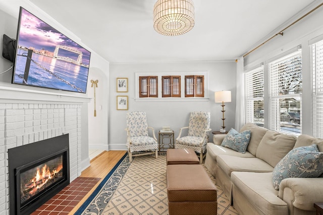 living room featuring baseboards, wood finished floors, ornamental molding, and a fireplace