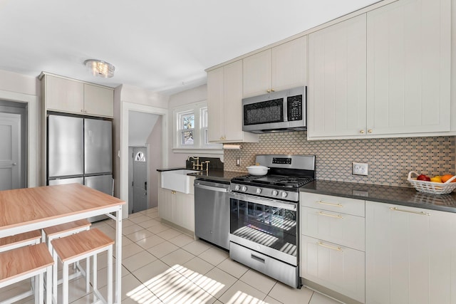 kitchen with dark countertops, light tile patterned flooring, backsplash, and stainless steel appliances