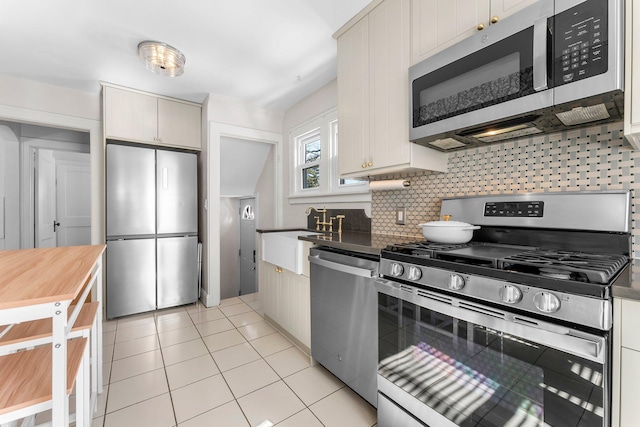 kitchen featuring a sink, light tile patterned flooring, tasteful backsplash, and stainless steel appliances