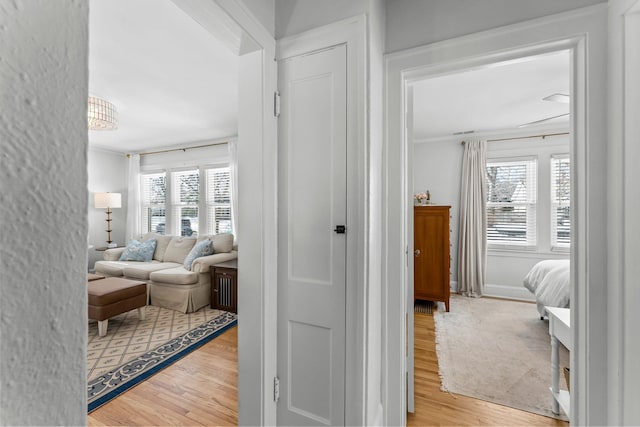 hallway with crown molding, wood finished floors, and baseboards