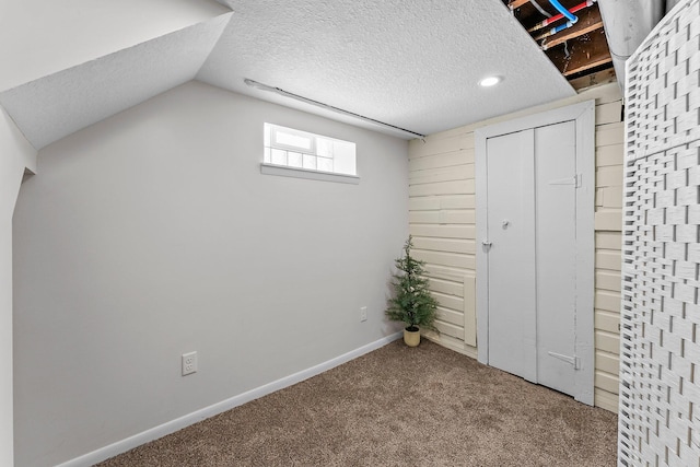 below grade area featuring carpet flooring, baseboards, and a textured ceiling