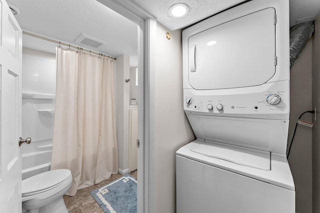 clothes washing area with stacked washer / dryer, a textured ceiling, laundry area, and visible vents