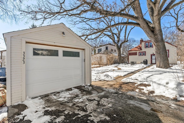 snow covered garage with a garage and driveway