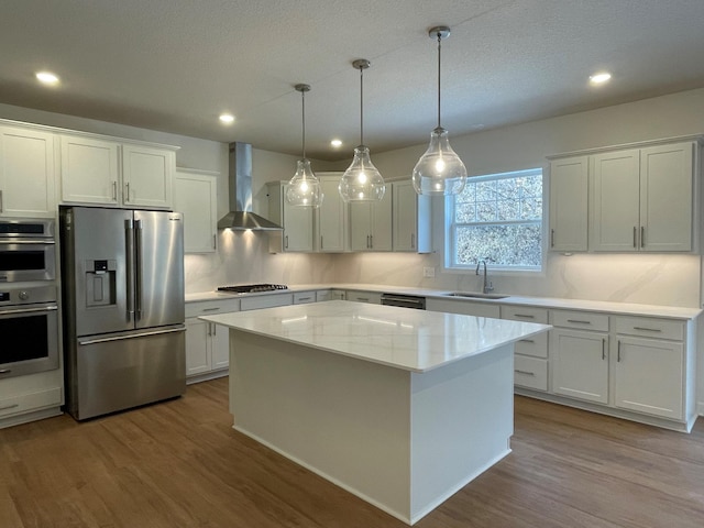 kitchen with white cabinets, a center island, stainless steel appliances, and wall chimney exhaust hood