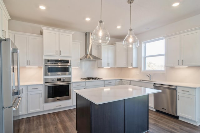 kitchen featuring white cabinets, pendant lighting, wall chimney range hood, and appliances with stainless steel finishes