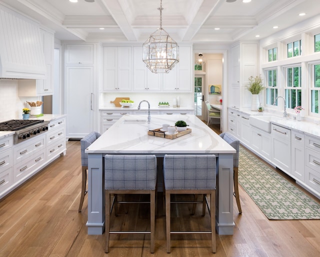 kitchen with stainless steel gas stovetop, sink, an island with sink, and a breakfast bar