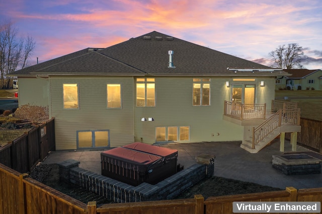 back house at dusk featuring a patio area and a hot tub