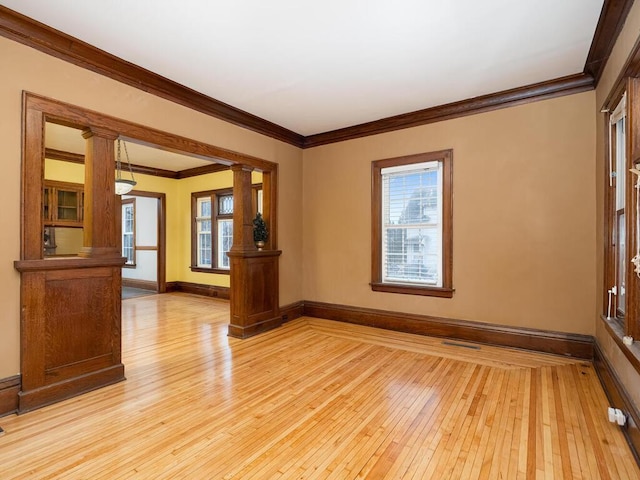 unfurnished room with ornamental molding, baseboards, decorative columns, and light wood finished floors