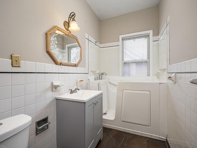 full bathroom with a tub to relax in, vanity, toilet, and tile walls