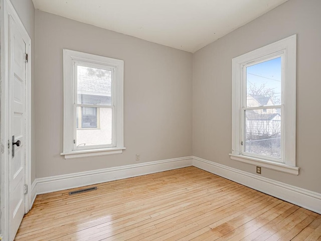 unfurnished room with light wood-style floors, visible vents, and baseboards