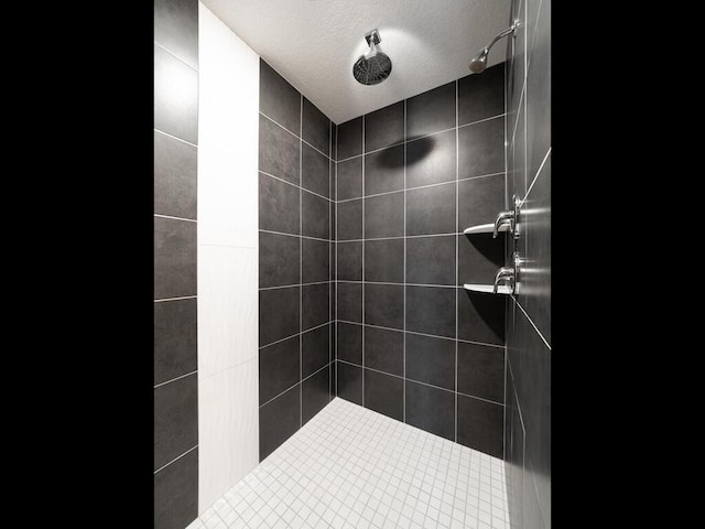 bathroom with a tile shower and a textured ceiling