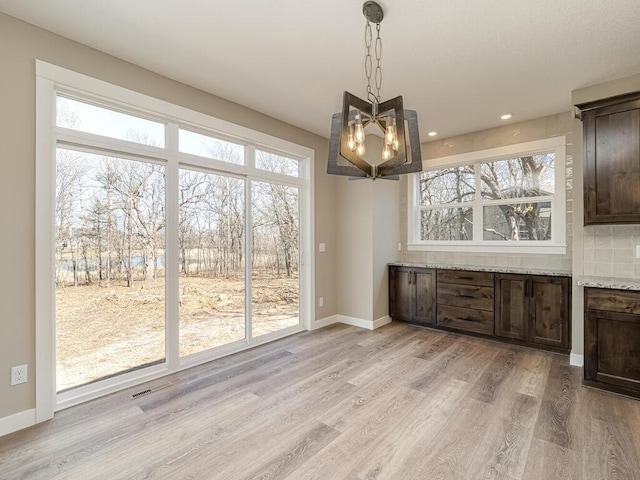 unfurnished dining area with a chandelier, light hardwood / wood-style floors, and plenty of natural light