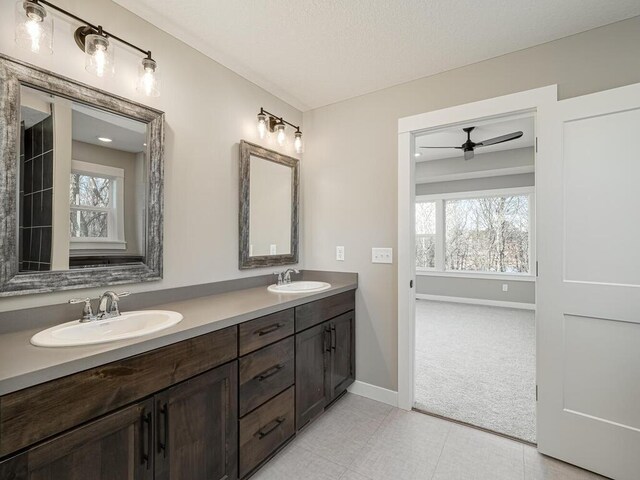 bathroom with ceiling fan, tile patterned flooring, vanity, and a textured ceiling