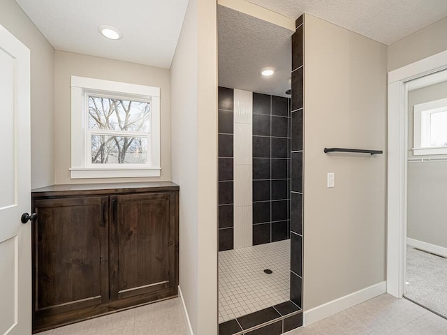 bathroom with plenty of natural light, a tile shower, and a textured ceiling