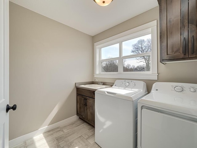 clothes washing area with washer and dryer, cabinets, and sink