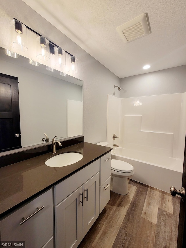 full bathroom with hardwood / wood-style flooring, vanity, shower / bathing tub combination, and a textured ceiling