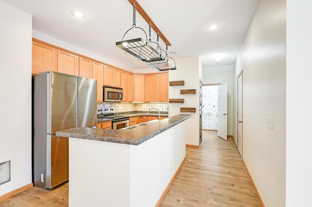 kitchen featuring sink, stainless steel appliances, tasteful backsplash, an island with sink, and light wood-type flooring