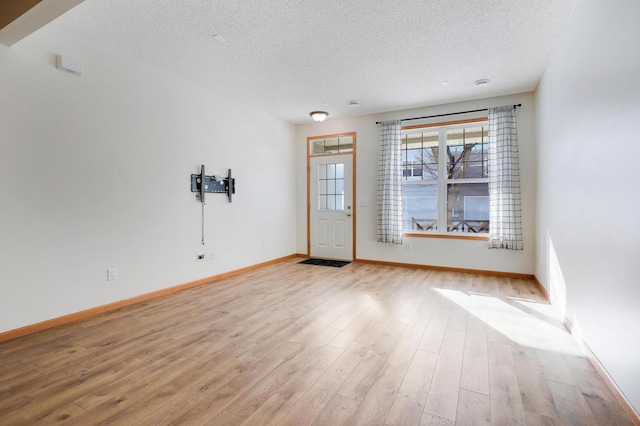 empty room featuring a textured ceiling and light wood-type flooring