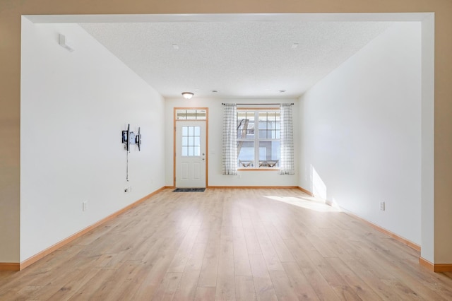 empty room featuring a textured ceiling and light hardwood / wood-style flooring