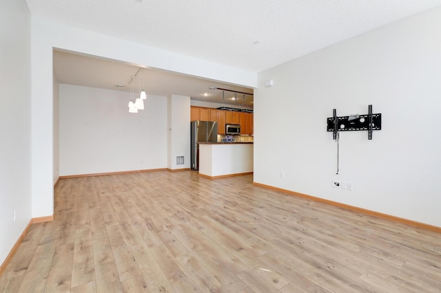 unfurnished living room with a textured ceiling and light wood-type flooring