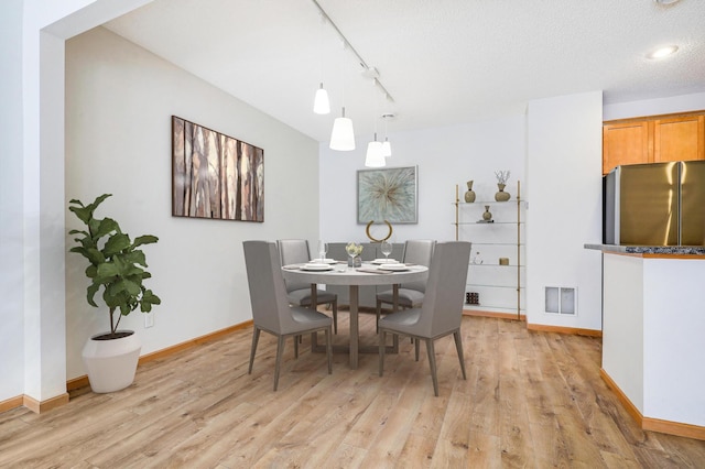 dining room with rail lighting and light wood-type flooring