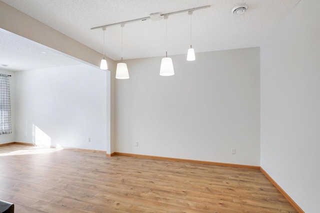 unfurnished room with light hardwood / wood-style flooring, a textured ceiling, and track lighting