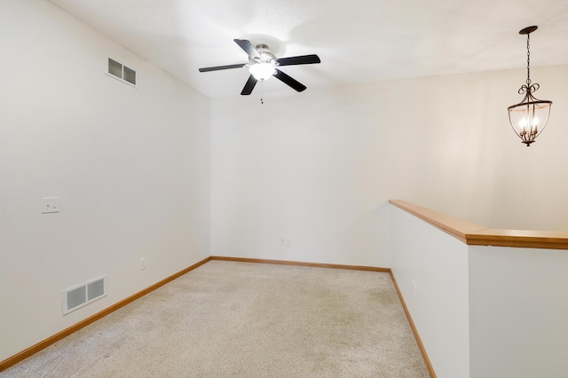 carpeted spare room with ceiling fan with notable chandelier