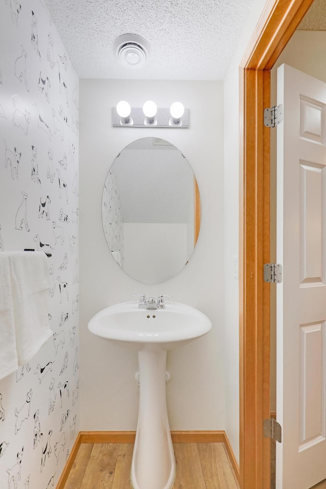 bathroom featuring wood-type flooring and a textured ceiling