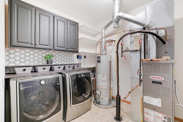 laundry room with gas water heater, washing machine and dryer, cabinets, and a textured ceiling