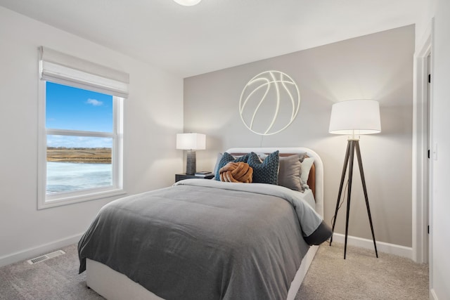 bedroom featuring light carpet and a water view