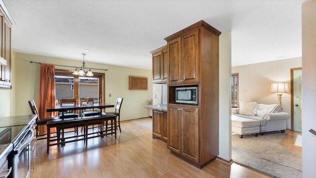 kitchen featuring pendant lighting, stainless steel appliances, light wood-type flooring, and an inviting chandelier