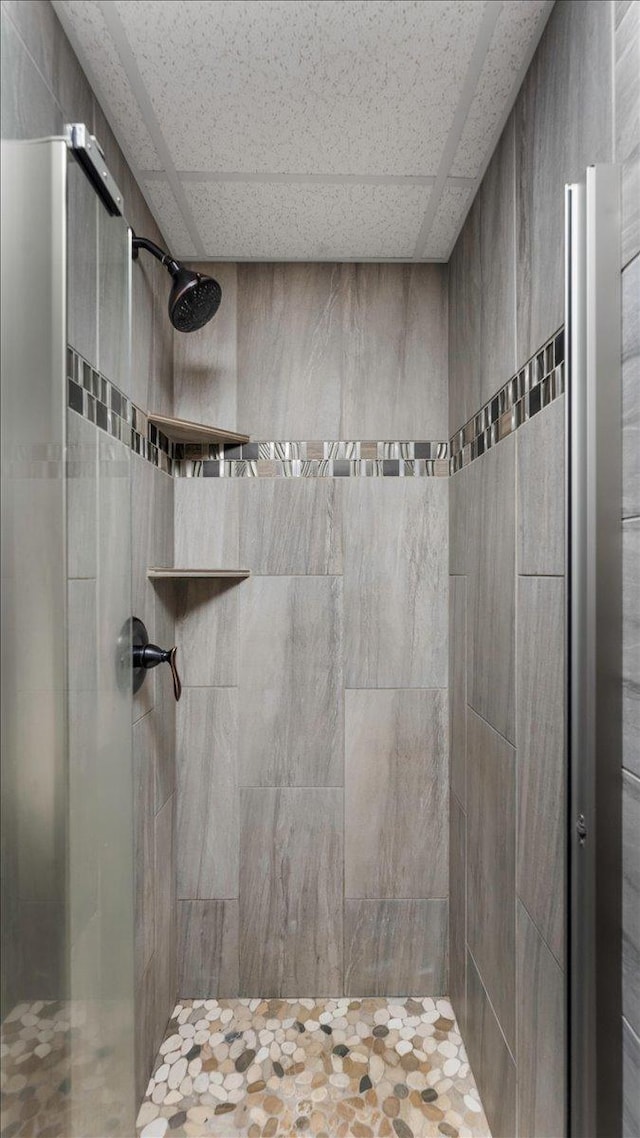 bathroom with a drop ceiling and a tile shower