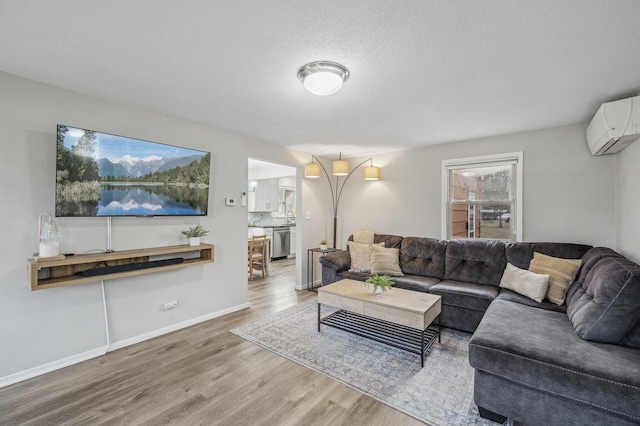 living room featuring hardwood / wood-style flooring, a wall mounted AC, and a textured ceiling