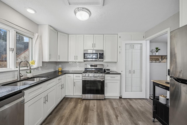 kitchen with sink, wood-type flooring, stainless steel appliances, and white cabinets