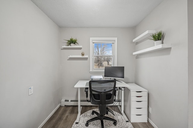 office space featuring dark hardwood / wood-style flooring, a baseboard heating unit, and a textured ceiling