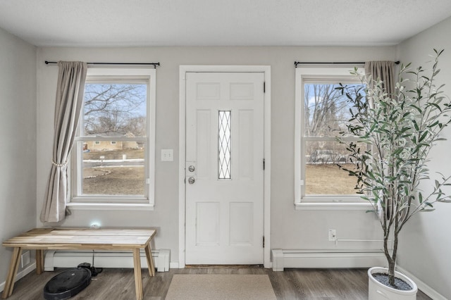 foyer entrance with baseboard heating, hardwood / wood-style floors, and a textured ceiling