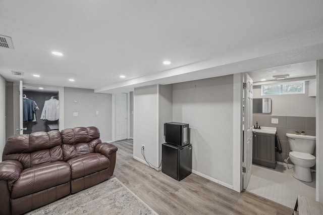 living room with sink, light hardwood / wood-style floors, and tile walls