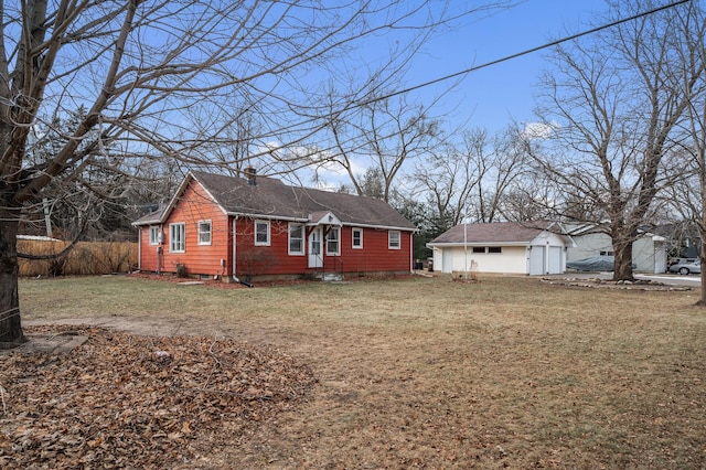 view of front of house featuring a garage, an outdoor structure, and a front lawn