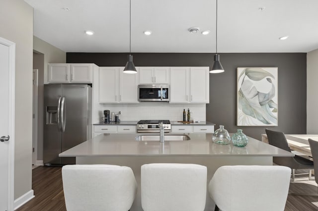 kitchen featuring white cabinets, a center island with sink, hanging light fixtures, and appliances with stainless steel finishes