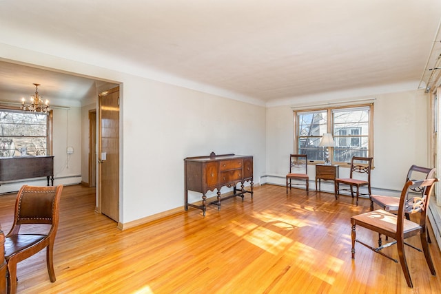 sitting room featuring a baseboard radiator, a chandelier, and light wood-type flooring