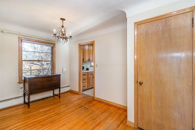 interior space featuring an inviting chandelier, a baseboard radiator, and light hardwood / wood-style floors