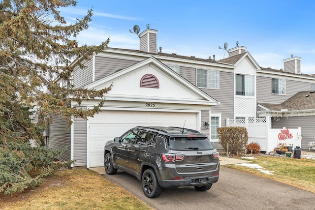 multi unit property featuring aphalt driveway and an attached garage