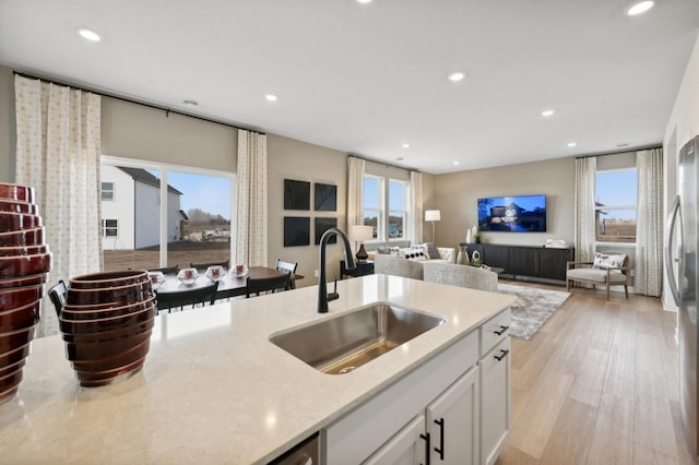 kitchen featuring light hardwood / wood-style flooring, white cabinetry, a healthy amount of sunlight, and sink